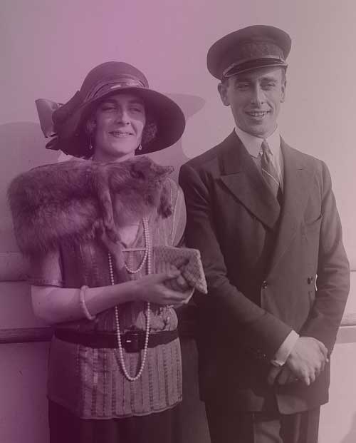 The owner of the Mountbatten tiara, Lady Edwina Mountbatten, with her husband, Lord Louis Mountbatten. They're standing together, smiling. Edwina is dressed in the height of 1920s fashion, with a fox stole and short-sleeve blouse belted low on her hips. Louis is in his naval uniform.